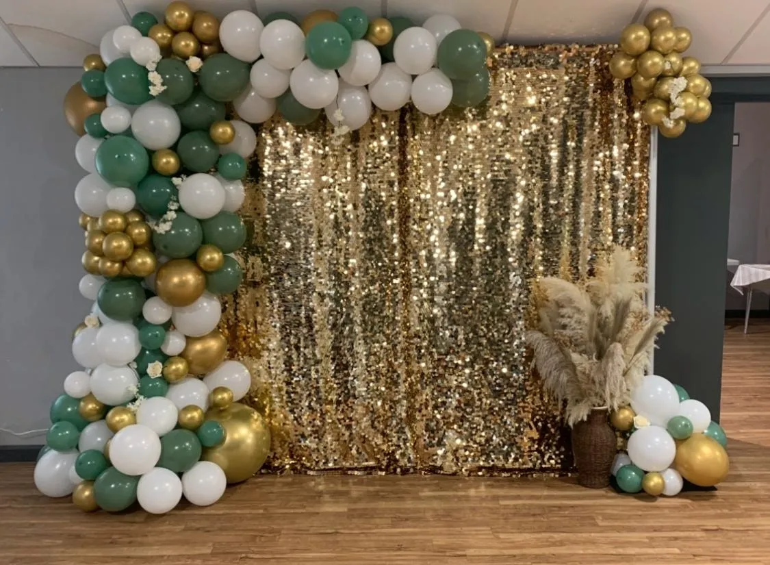 Gold sequin backdrop framed by a green, white and gold balloon garland