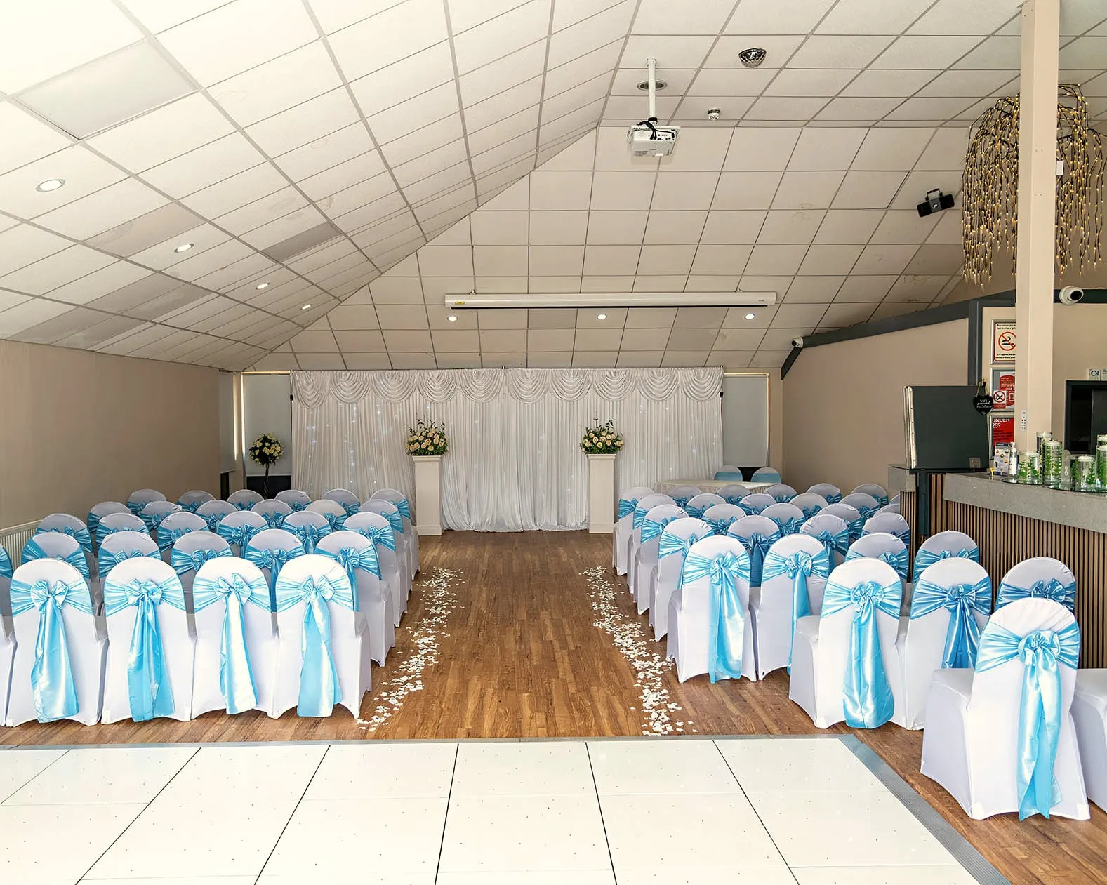 The room set for a ceremony, with rows of chairs facing a draped backdrop