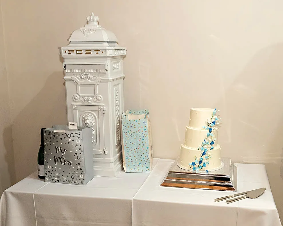 White post box for cards beside a wedding cake