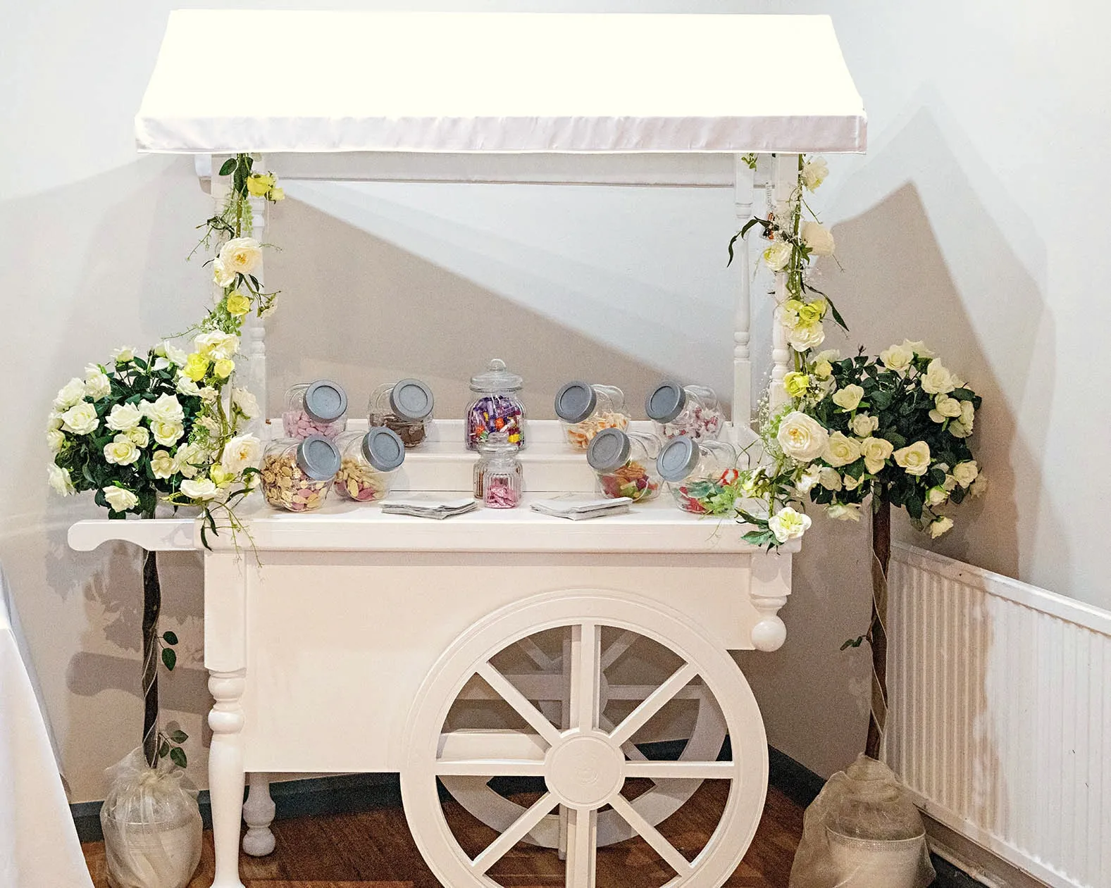 White sweet cart with jars of sweets and floral trees